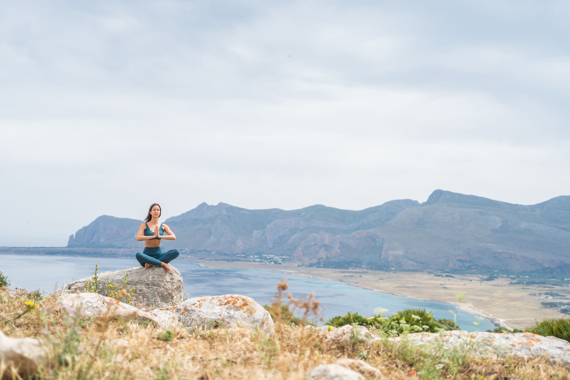 Young woman meditates at coastal viewpoint